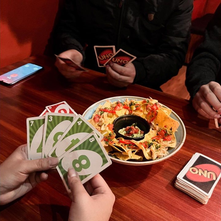 Amigos jugando a las cartas alrededor de una mesa en Catrinka